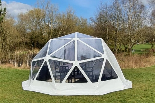 A grass campsite with a dome from TruDomes