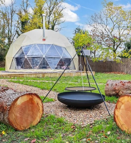 A grass campsite with a table and a dome from TruDomes
