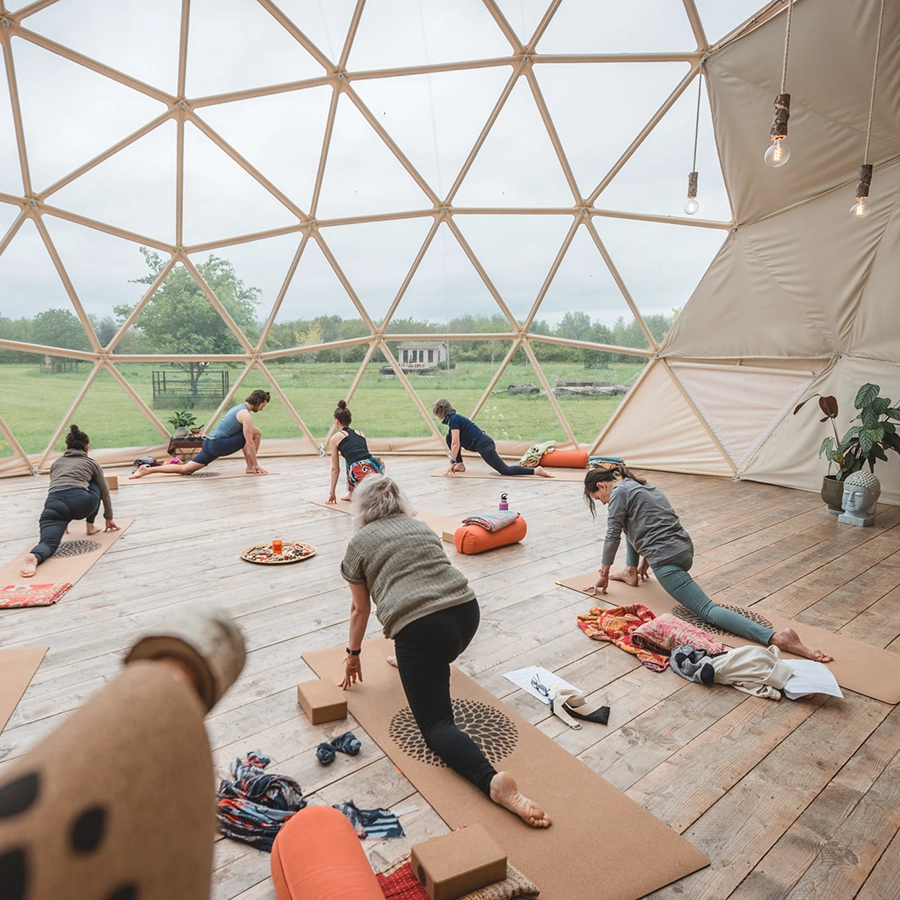 A large dome from TruDomes with wooden flooring that has a yoga class taking place in it.